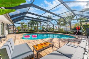 a pool with a glassconservatory with a table and chairs at Casa De Olas - Waterfront Luxe Home - Heated Pool - Game Room - Boat Lift - Minutes to Beach in Cocoa Beach