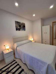 a bedroom with a large white bed and two lamps at Apartamento El Morche Playa in Morche