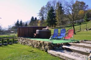 a group of three chairs sitting on a rock wall at Domček u Alina in Žiar