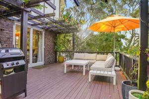patio con ombrellone, divano e tavolo di Seaside Bougainvillea Retreat close to Beaches ad Auckland