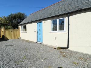 a white garage with a blue door and a window at Cornel Clud in Cemaes Bay