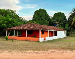 a red and white house with trees in the background at Casa Raizes Pousada in Ilha Cotejuba