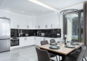 a kitchen with white cabinets and a wooden table and chairs at Christian Luxury Villa in Tsilivi