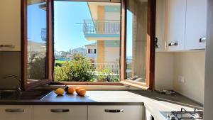 a kitchen with a large window and oranges on the counter at I Marosi Beach Apartment in Lido di Fermo