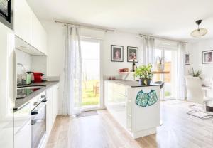a kitchen with white cabinets and a large window at Casa Via - Entre Caen & la mer in Cambes-en-Plaine +4 photos