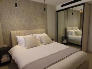 une chambre avec un grand lit blanc avec un miroir dans l'établissement GOLDEN SAND Suite, à Eilat 24 autres photos