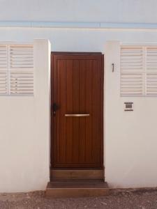 eine Holztür in einem weißen Gebäude mit zwei Fenstern in der Unterkunft CASA CALMA y LUZ in El Pozo de los Frailes