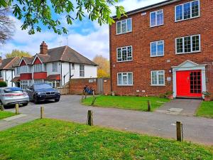 a large brick building with a red door at Elisha's City Apartment in Hackbridge