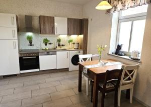 a kitchen with white cabinets and a table with chairs at FeWo Hottelstedt in Hottelstedt