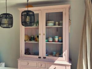 einem Schrank mit Geschirr mit zwei Hängeleuchten in der Unterkunft Salty - Vakantiehuisje op de grens van Bredene-De Haan in Bredene + 17 Fotos
