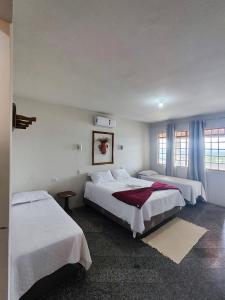 a hotel room with two beds and two windows at Hotel Montanhas de Minas in Diamantina