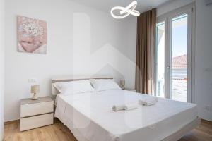 アルバ・アドリアティカにあるHomiday - Residenza Incantoの大きな白いベッドと窓のある白い寝室