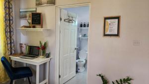 Sunsetcrest Tranquil Getaway في Anse La Raye: حمام مع مكتب وجهاز كمبيوتر محمول على طاولة