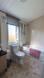 a bathroom with a toilet and a tub and a window at Dune Haven Luxury Beachside Lodge in Lossiemouth +57 photos