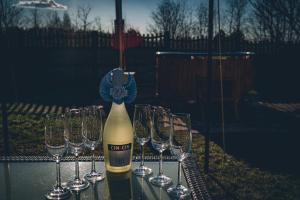 a bottle of wine with four wine glasses on a table at Romantyczny Domek in Kalej