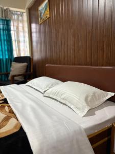 a bed with two white pillows and a wooden wall at Sparid Inn in Darjeeling