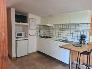 Una cocina con gabinetes blancos y encimera. en El Valle, en Piedralaves