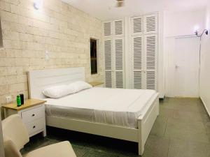 a bedroom with a white bed and a table and a chair at Englishpoint Marina Villa in Mombasa
