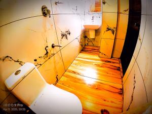 a dirty bathroom with a toilet and a wooden floor at Pool View Resort in Cochin
