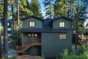 a green house with a deck in the woods at 4BD Home - Games - Close to Downtown & Snowbowl in Flagstaff