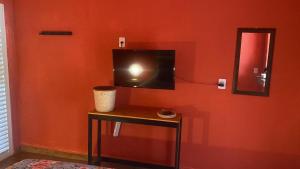 a room with a table with a television on a wall at CHALÉS MARICOTA in Vargem Bonita