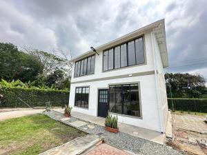 a white house with black windows and a yard at Almendros 1- Apartamento rural con aire acondicionado in Armenia