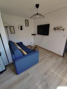 un divano blu in un soggiorno con TV a schermo piatto di ThiLuCha Le ThiLu ALPE D'HUEZ gd domaine à Allemont ad Allemont