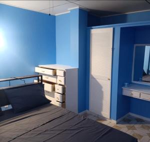 1 dormitorio con pared azul, cama y espejo en Michael's Beach Complex #3, en Brighton Village
