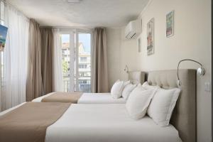 two beds in a hotel room with a window at Hotel des Congrès et Festivals in Cannes
