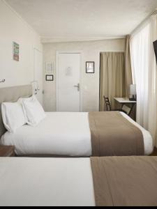 a hotel room with two beds and a desk at Hotel des Congrès et Festivals in Cannes