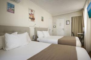 a hotel room with two beds and a table at Hotel des Congrès et Festivals in Cannes
