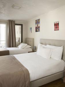 two beds in a hotel room with white walls at Hotel des Congrès et Festivals in Cannes