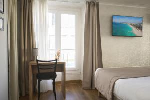 a hotel room with a desk and a bed and a window at Hotel des Congrès et Festivals in Cannes