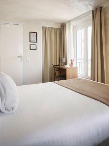 a bedroom with a large white bed and a desk at Hotel des Congrès et Festivals in Cannes