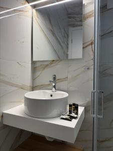 a white bathroom with a sink and a mirror at RoomElioti Apartments in Ofrínion +79 photos