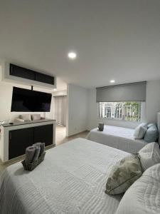 una camera da letto con due letti e una TV a schermo piatto di 102 loft la merced- casa saza a Cali Altre 34 foto