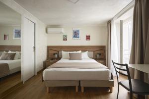 a bedroom with a bed and a desk with a chair at Hotel des Congrès et Festivals in Cannes