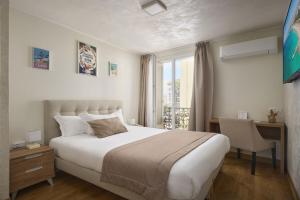 a bedroom with a bed and a desk and a window at Hotel des Congrès et Festivals in Cannes