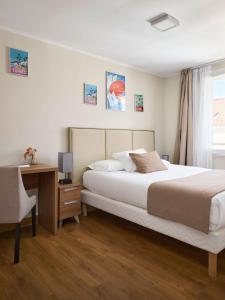 a bedroom with a bed and a desk and a window at Hotel des Congrès et Festivals in Cannes
