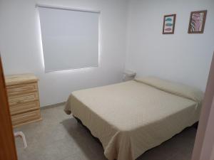 Un dormitorio con una cama y una cómoda y una ventana. en Departamentos TUNQUELEN, en Río Colorado