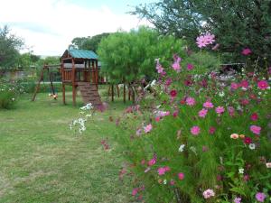 um parque infantil num jardim com flores cor-de-rosa em Cabañas Mandala em San Marcos Sierras