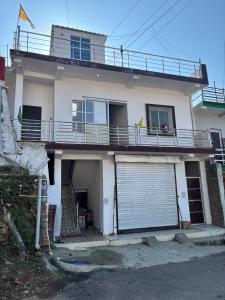 una casa bianca con cancello e garage di Surkanda Home stay a Nākuri