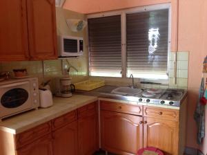 a kitchen with a microwave and a sink and a window at Sun Caraibes in Orient Bay