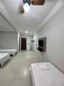 a room with two beds and a flat screen tv at Apartamento 101 - Suíte ampla para grupos e empresas in Patos de Minas