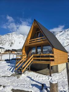 una cabina in legno nella neve con una montagna di Kazbegi Folk Cottages a Kazbegi