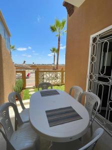 a white table and chairs on a balcony with palm trees at Kawtar in Pont Blondin