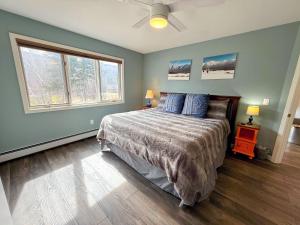 a bedroom with a bed with blue walls and two windows at F32 Modern Golf Course Home with Mountain Views in Bretton Woods