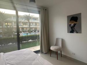 a bedroom with a bed and a chair and a window at Hotel apartment G Cribs Hotel in Hurghada