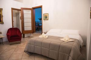 a bedroom with a bed and a red chair at L'ulivo - A due passi dal Mare in Mola di Bari
