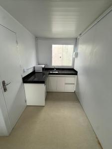 Una pequeña cocina blanca con fregadero y ventana. en Studios Canaã, en Canaã dos Carajás